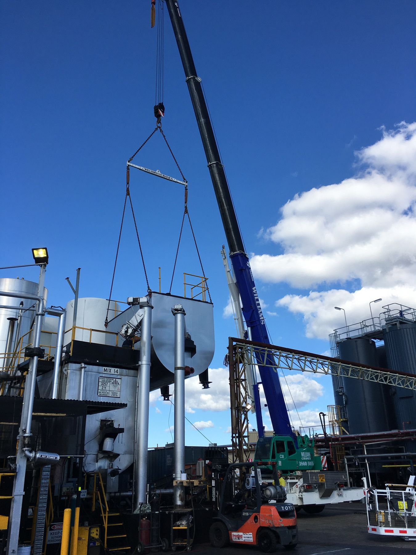Crane lifting a tank section into place at a bitumen plant